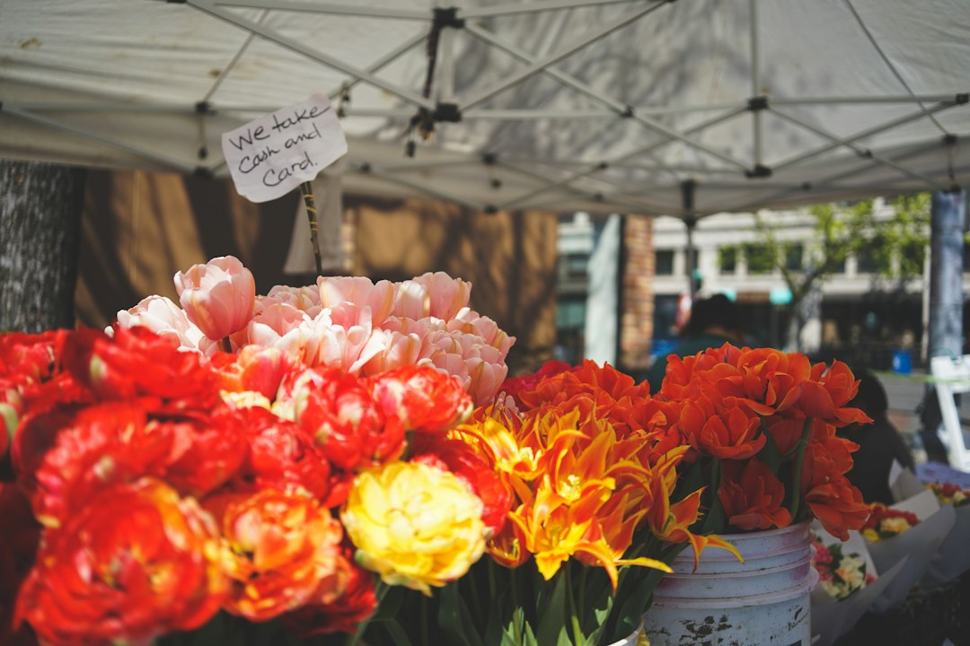 A colorful flower stall at a farm market with blooms in buckets