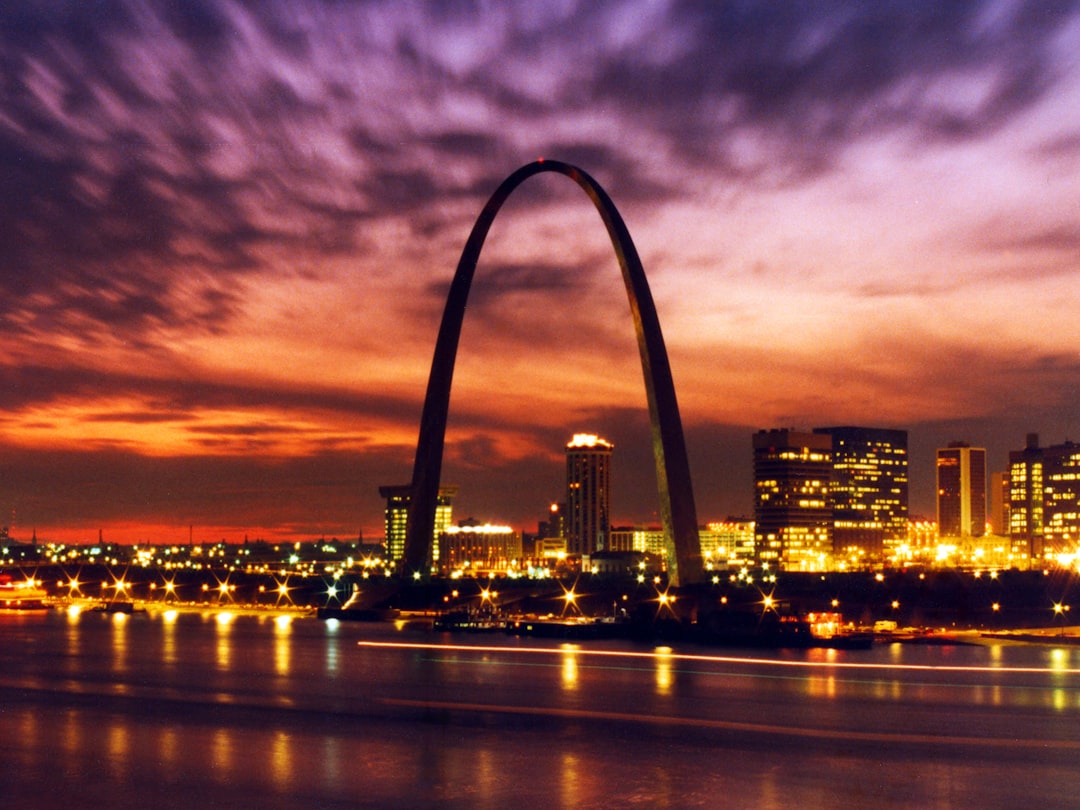 The illuminated Gateway Arch reflecting on the Mississippi River at night