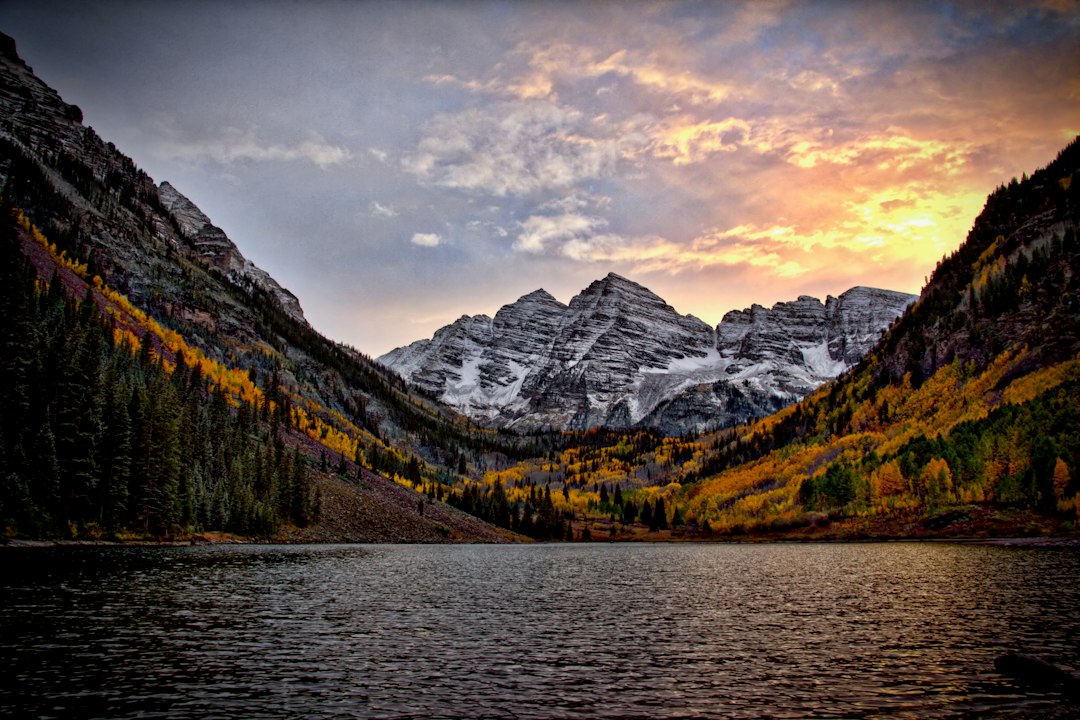 Maroon Bells reflected in Maroon Lake surrounded by golden aspens