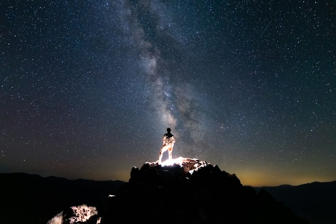 The Milky Way arches over a dark desert ridge under a brilliant night sky