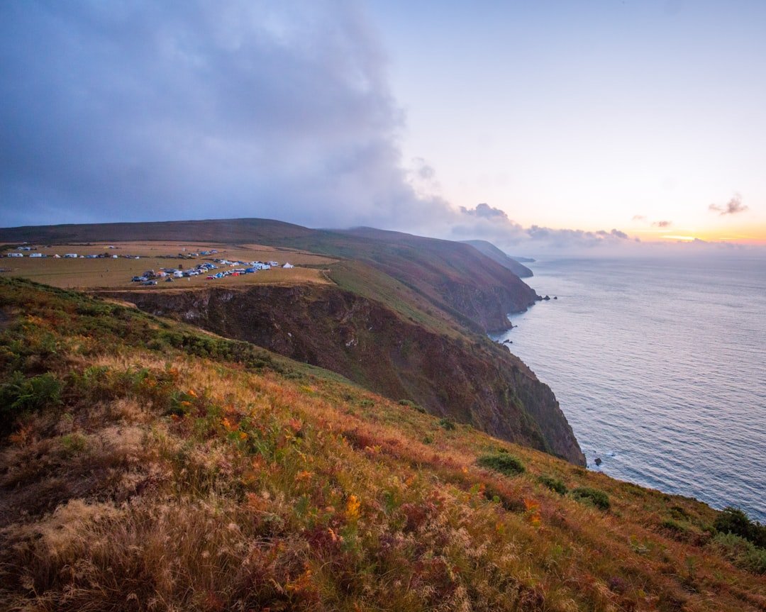 Tents on a grassy bluff campground overlooking the Pacific at sunset
