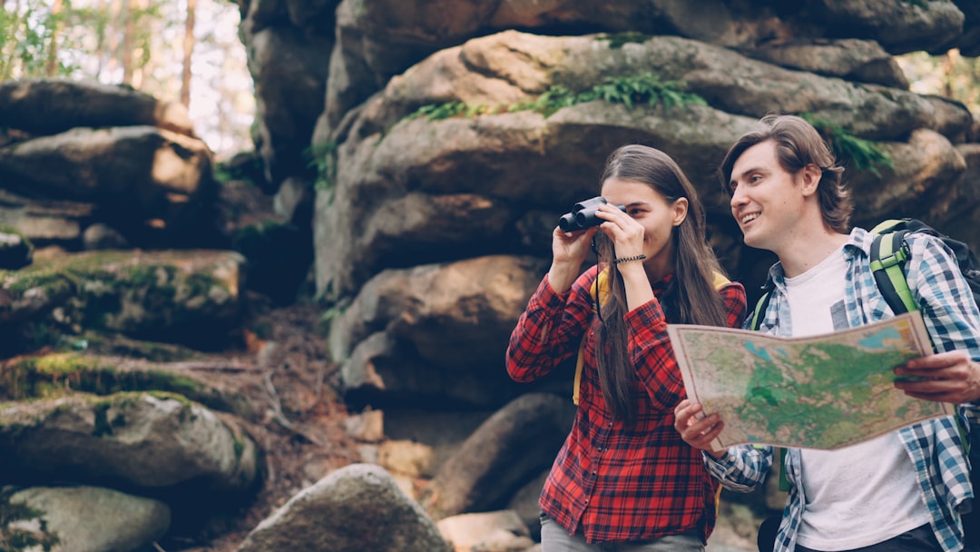 Travelers consulting a trail map with binoculars at hand in autumn woods