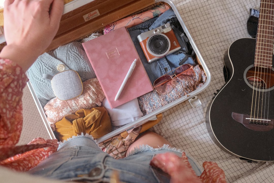 Open suitcase packed with folded clothes on a bed