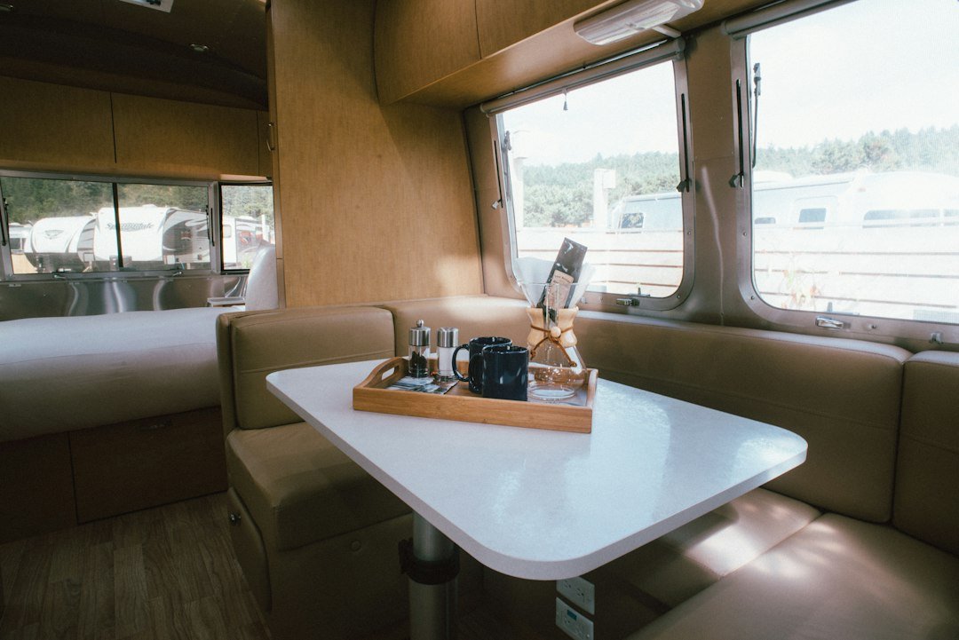 Cozy campervan interior with a small dining table, coffee setup, and upholstered bench seating