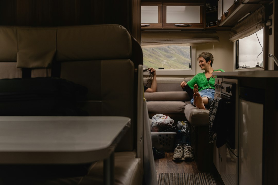 Relaxed seating inside a camper van with a hill view through the window
