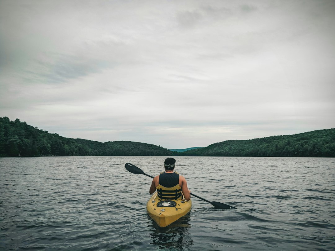 Paddler in a kayak on calm water surrounded by forest