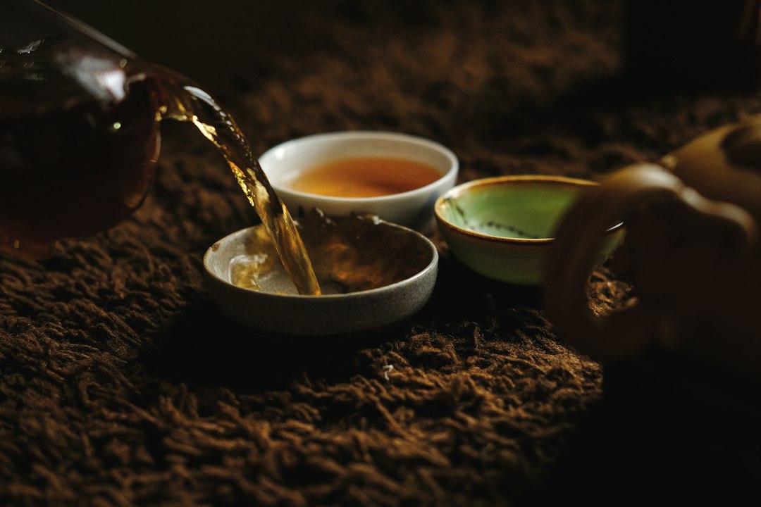 Hot tea being poured from a teapot into a small ceramic cup
