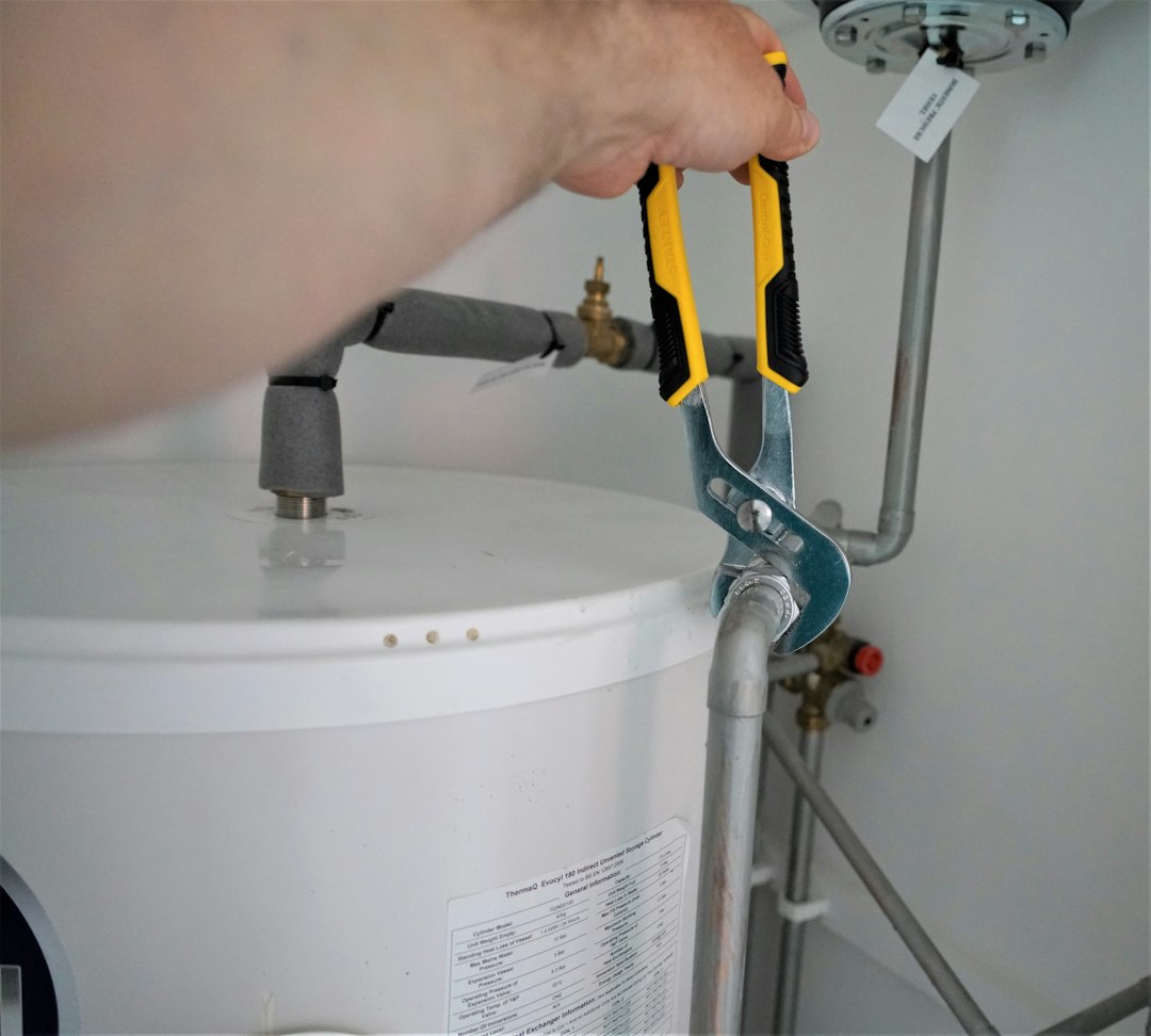 Water heater tank plumbing being worked on with hand tools