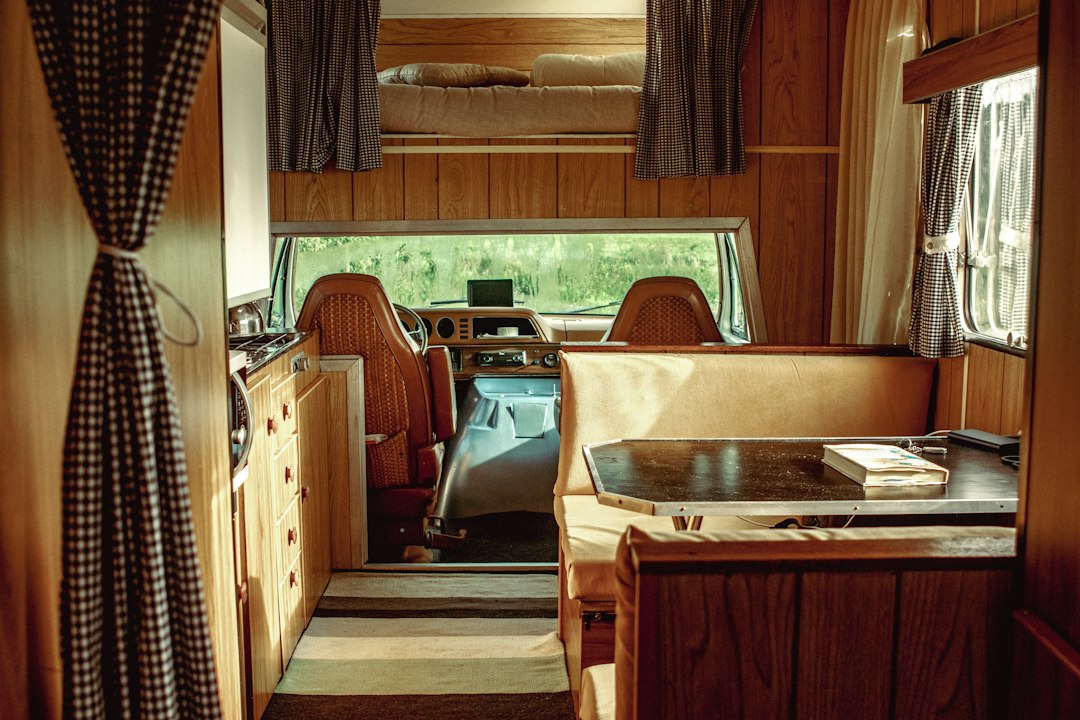 Vintage camper van interior with wood paneling, a dinette, and gingham curtains