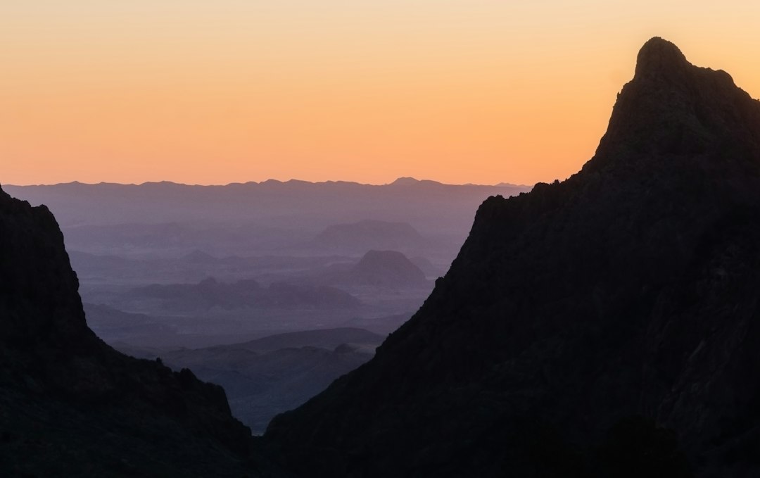 Desert mountain ridges silhouetted against a burning orange sunset in Big Bend country