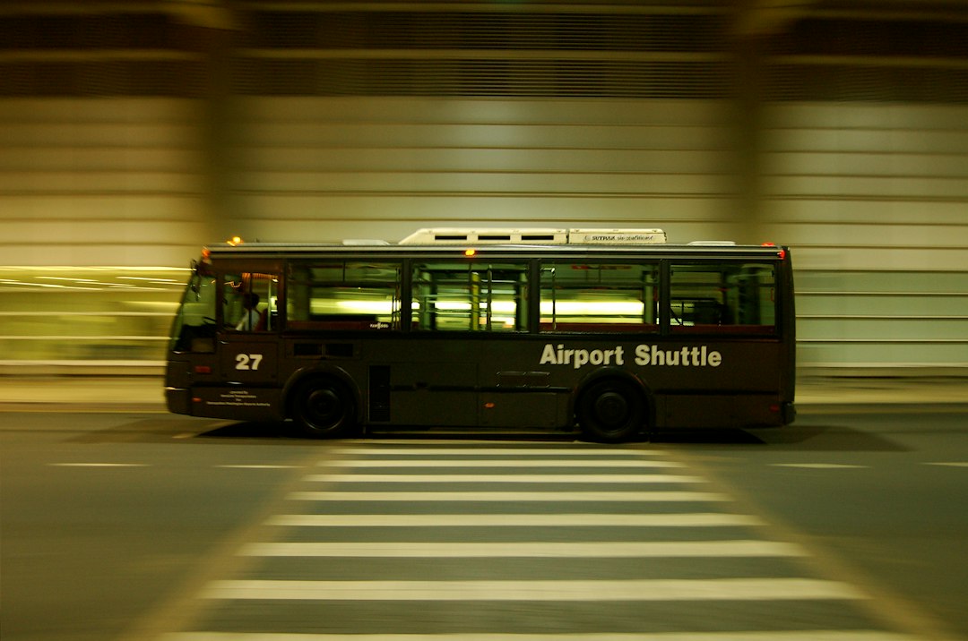 Traveler stepping off an airport rental car shuttle with luggage