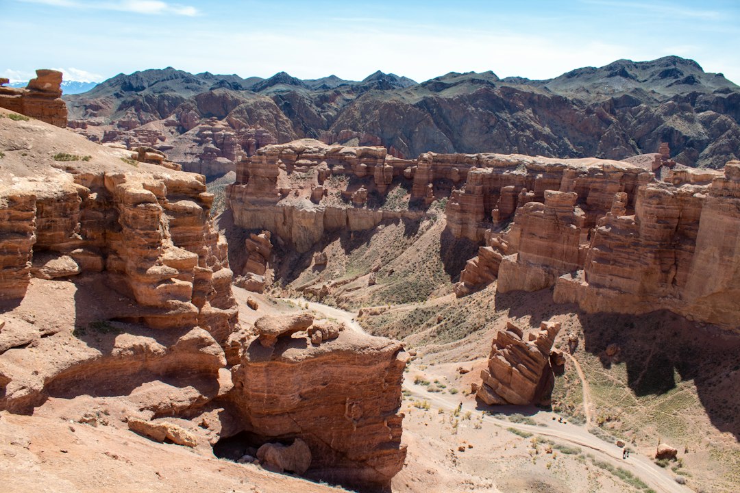 Deep canyon cut through reddish desert rock with distant mountains