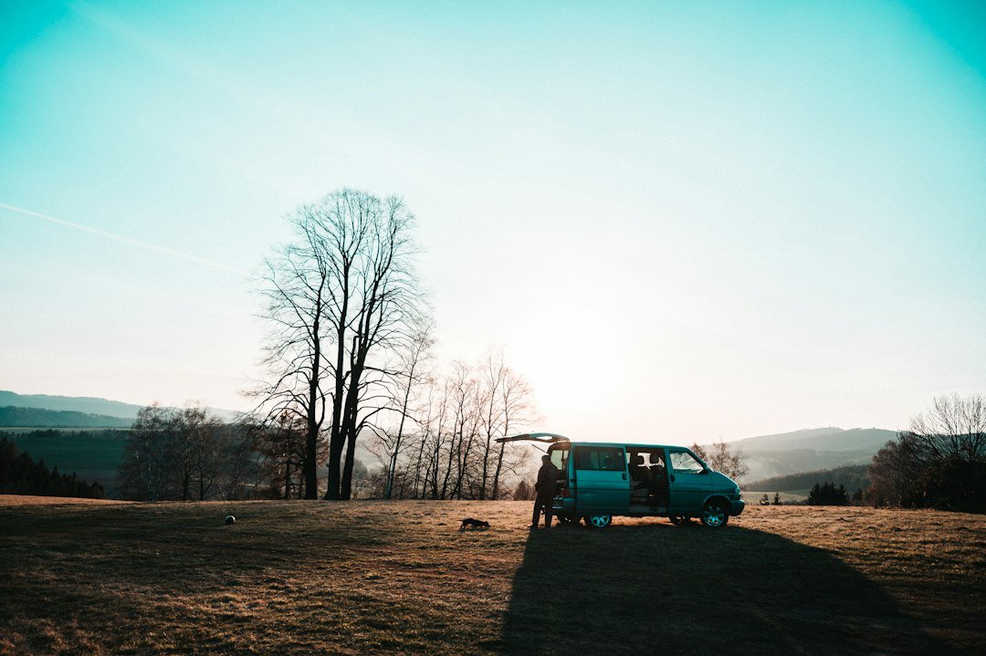Camper van parked in a scenic field at sunset with doors open