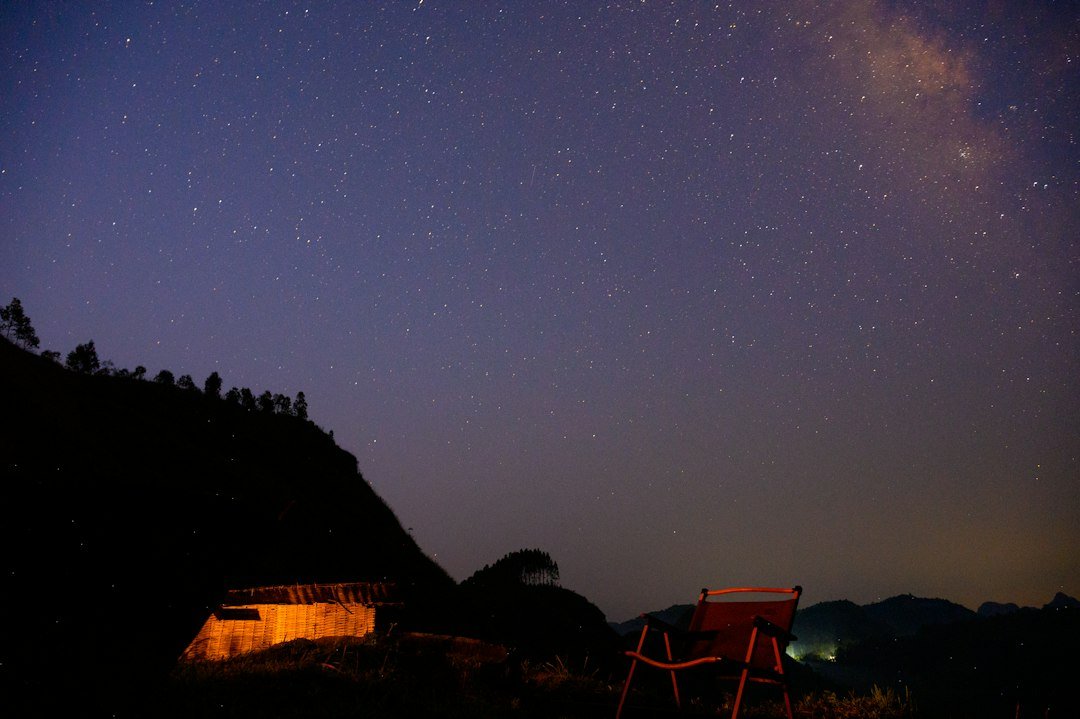 An empty camp chair facing the Milky Way on a dark hillside