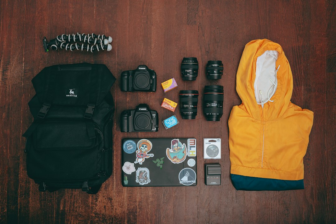 Flat lay of organized travel and camera gear including backpack and jacket