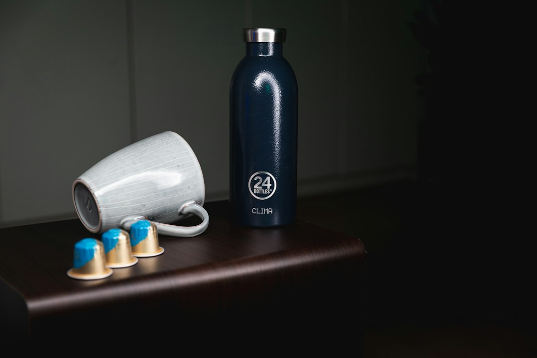 Insulated vacuum thermos bottle with mug on a table