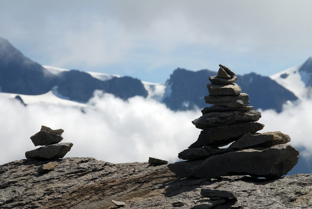Hiker standing beside a rock cairn at a windy summit