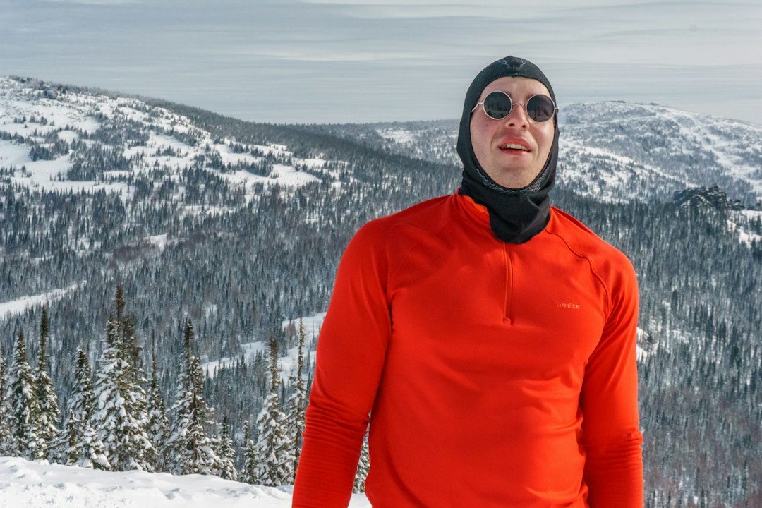 Traveler in a bright orange parka standing in deep snow