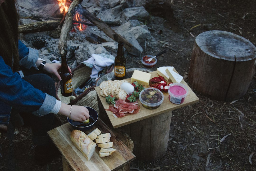Travelers sharing a picnic spread beside a campfire in the woods