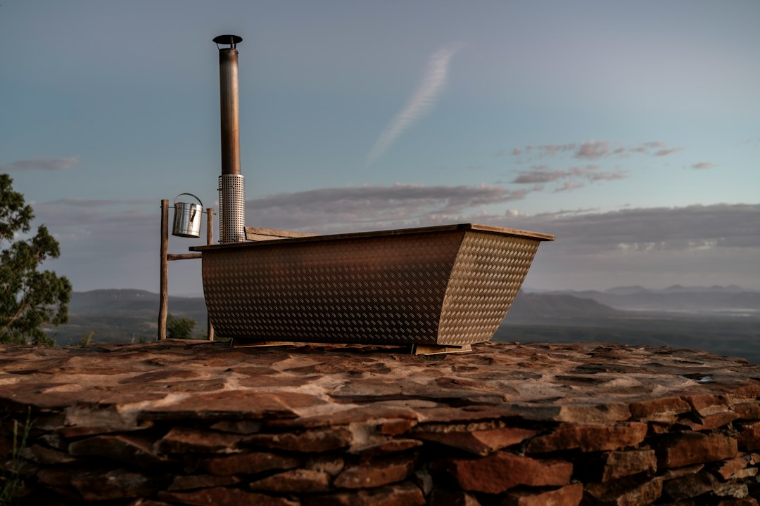 Outdoor cedar soaking tub beside a river at dusk