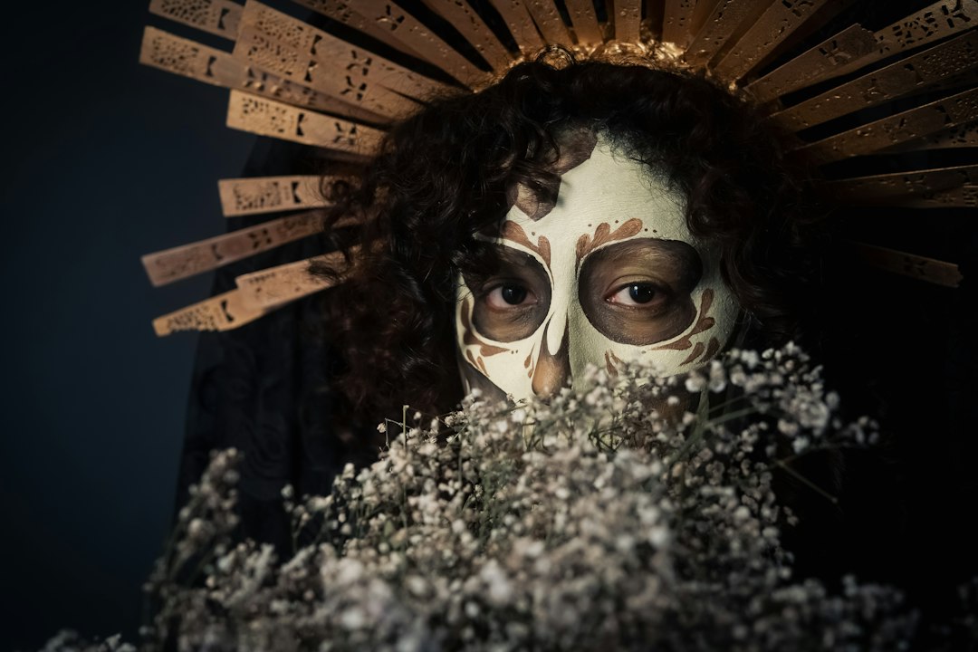 Close-up of Catrina skull face paint framed by white flowers
