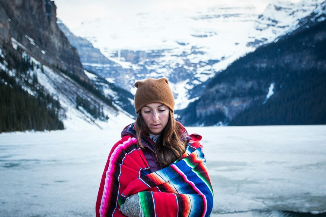 A traveler wrapped in a blanket on a frozen lakeshore