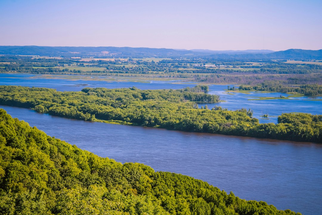A wide river winding past forested bluffs