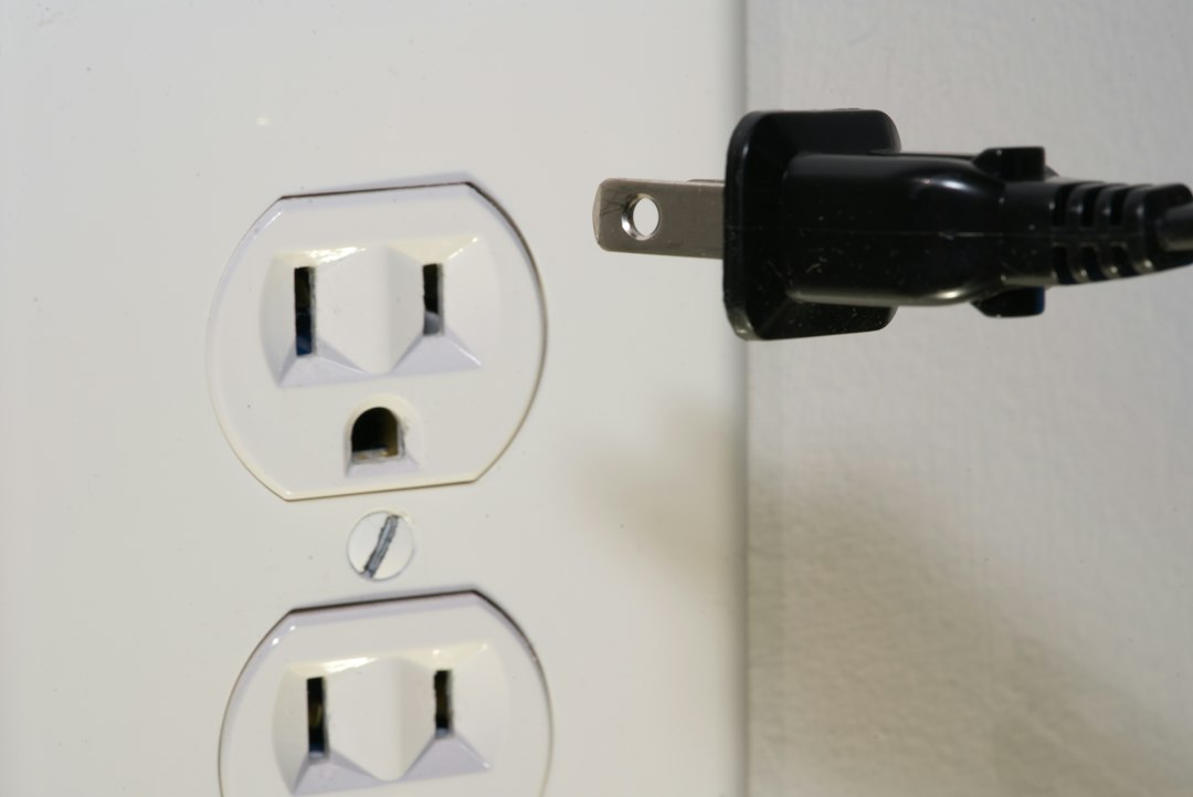 Power plug resting beside a wall outlet in a hotel room