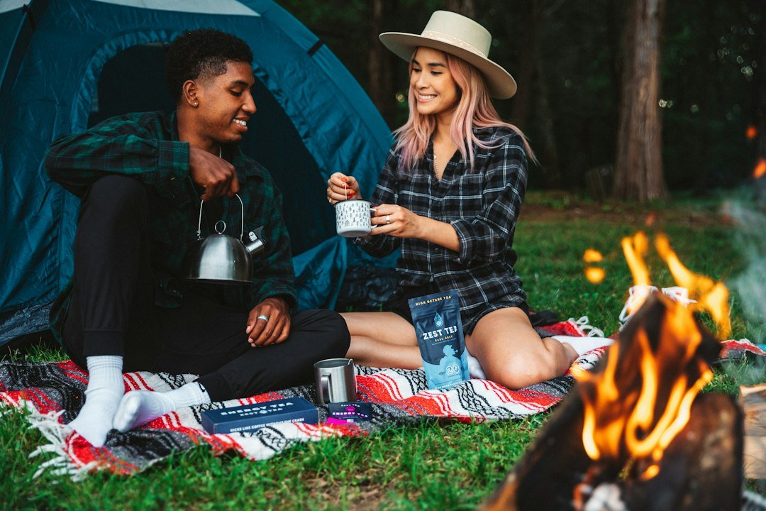 Two campers sharing a hot drink by a fire on a cold night