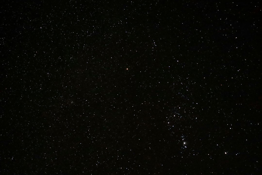 A dense star field with a bright orange star glowing near Orion's radiant