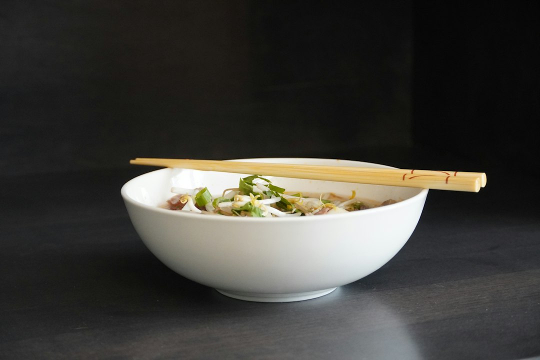 Bowl of instant ramen with chopsticks on a dark wooden table