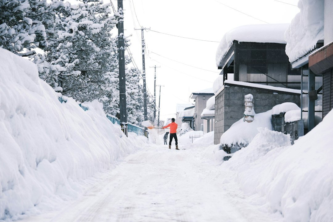 A person in an orange jacket shoveling a path through deep snow