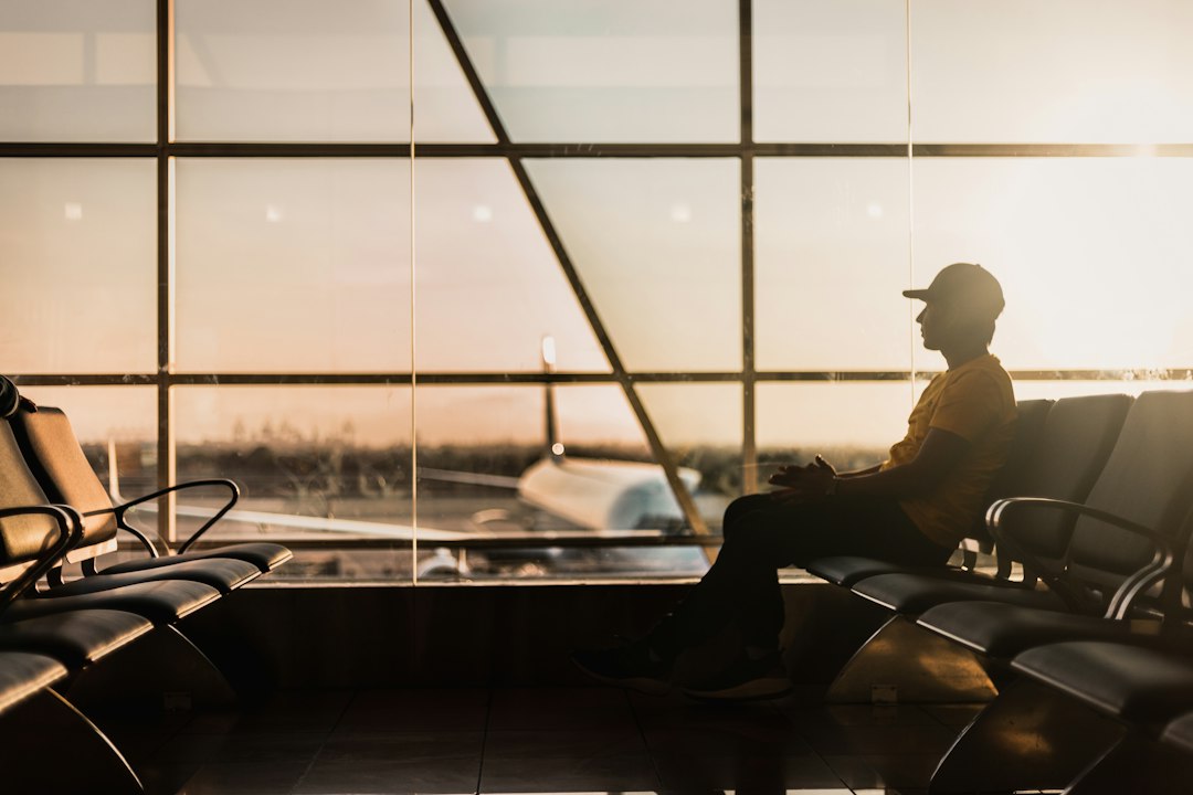 Traveler waiting alone in an airport terminal at golden hour, watching the tarmac