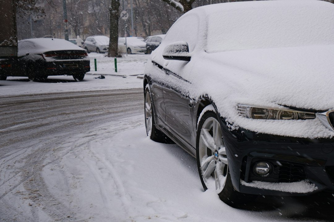 A sedan buried in snow on a city street after a snowstorm