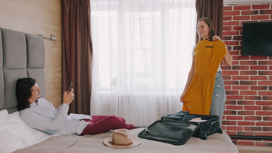 Traveler settling into a vacation rental bedroom beside an open suitcase