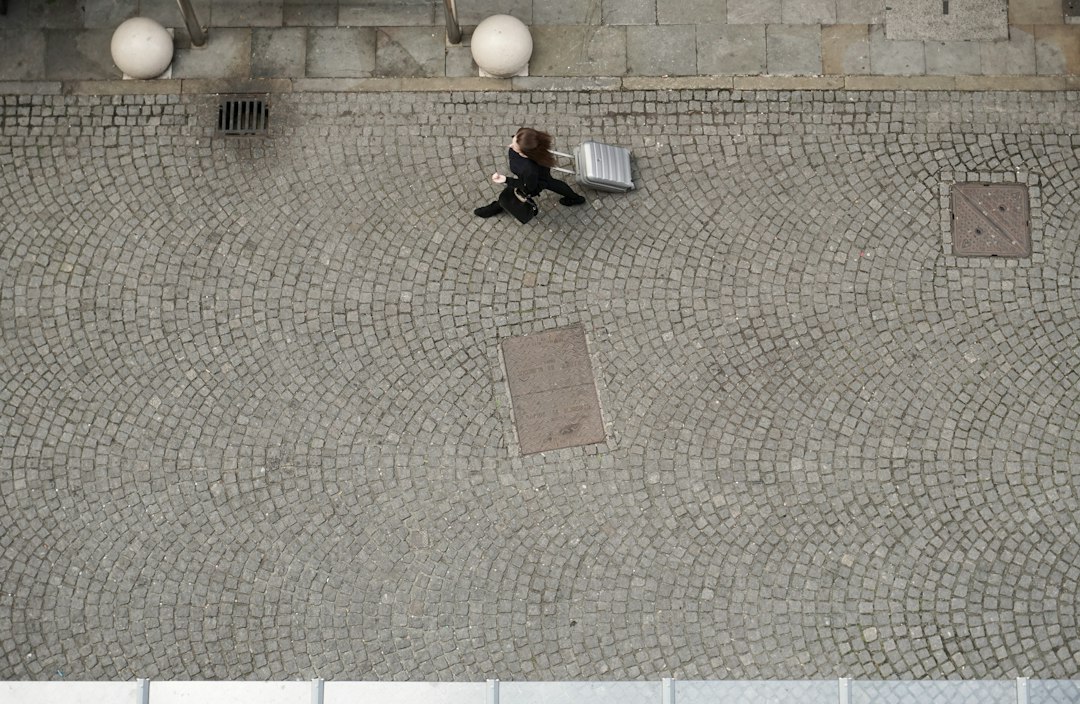 A traveler pulling a wheeled suitcase across a cobblestone street