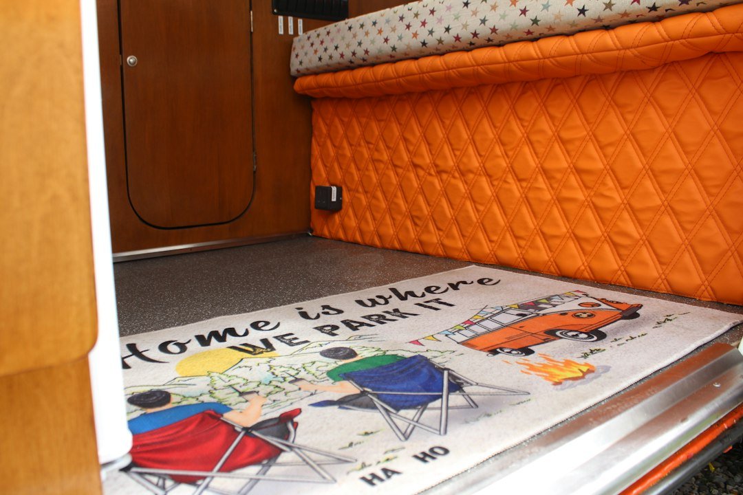 Campervan interior with quilted bench seating and bedding arranged into a bed