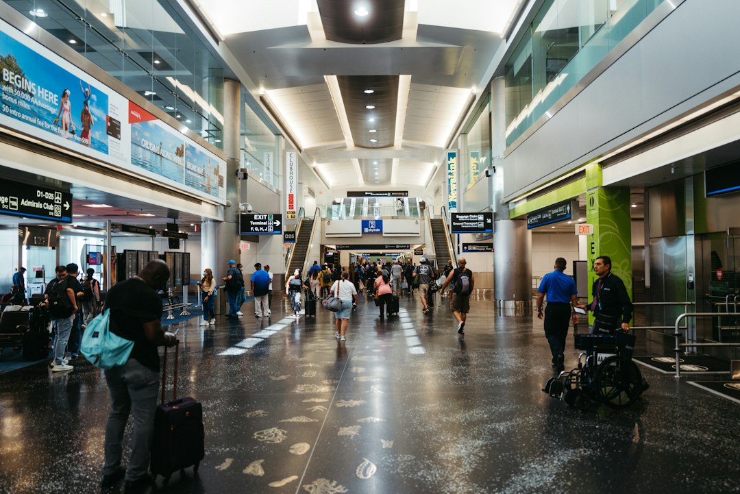 A traveler rolling a suitcase through a busy airport terminal